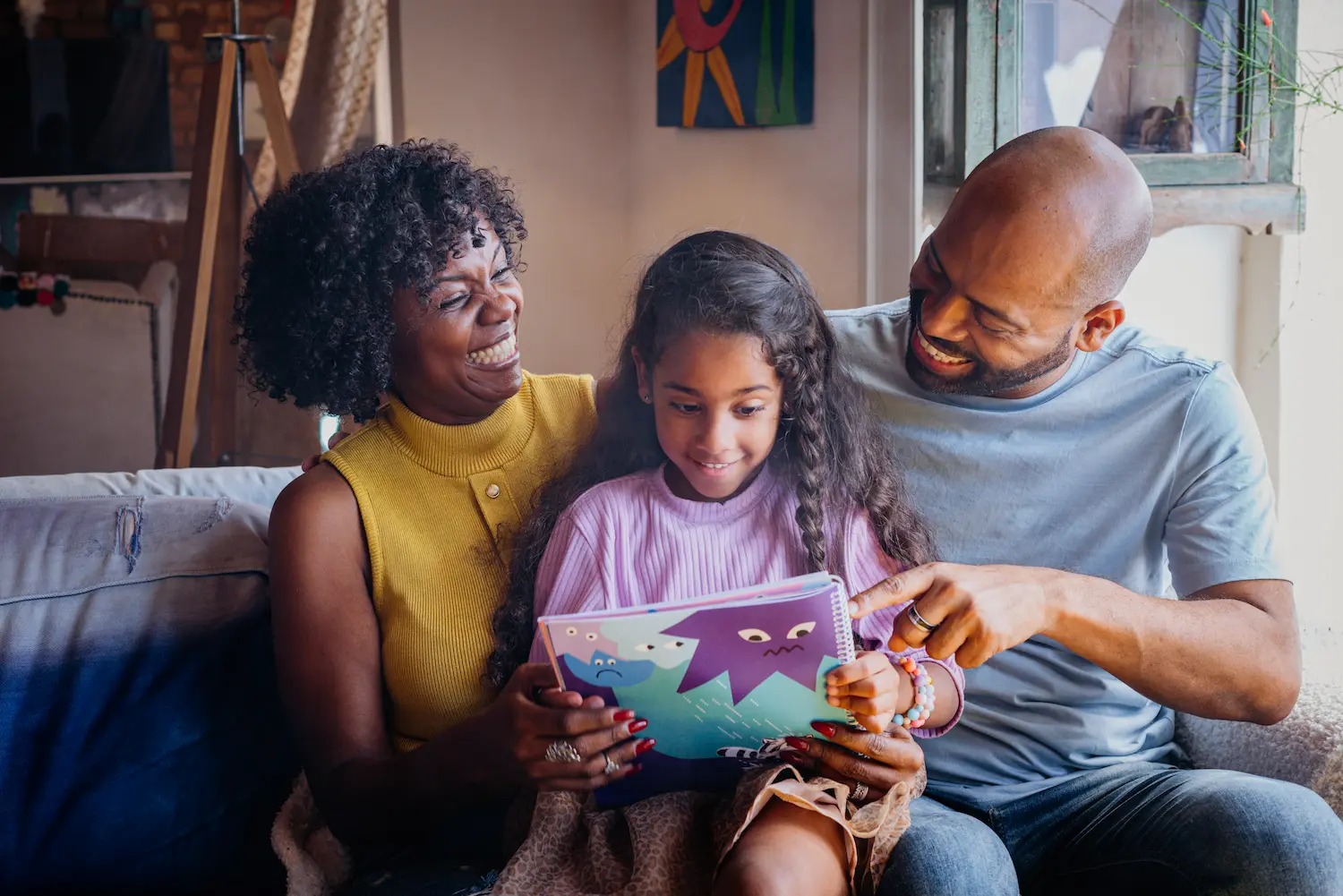 Pai e mãe leem livro ilustrado com a filha, simbolizando a literatura e educação